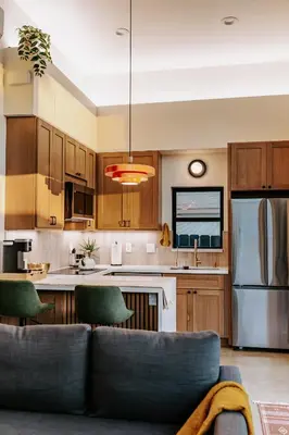 a kitchen with wooden cabinets and a couch in a room at Chic Casita w BBQ, Patio, Backyard - 4 min to SDSU, 15 mins to beach, Unit B in La Mesa