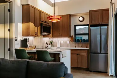 a kitchen with wooden cabinets and green chairs at Chic Casita w BBQ, Patio, Backyard - 4 min to SDSU, 15 mins to beach, Unit B in La Mesa