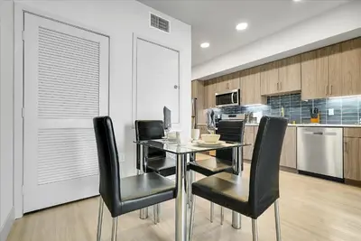 a dining room with a glass table and black chairs at Global Luxury Suites near Liberty Station in San Diego