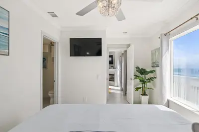 a white bedroom with a large bed and a chandelier at Luxury Oceanfront steps to Beach & Town, Best views! in Oceanside