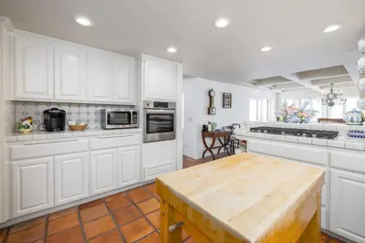 a kitchen with white cabinets and a wooden table at 4 Bedroom With Pool in Oceanside