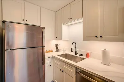 a kitchen with white cabinets and a stainless steel refrigerator at Stylish 1BR Near Downtown, Beaches & North Park in San Diego