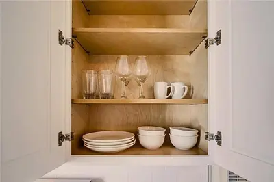 a cupboard with plates and bowls and glasses at Stylish 1BR Near Downtown, Beaches & North Park in San Diego