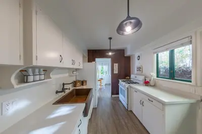 a kitchen with white cabinets and a sink at Redwood Hollow Cottages in San Diego
