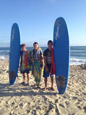 three men standing on the beach with their surfboards at Beach Oasis in Carlsbad Village in Carlsbad