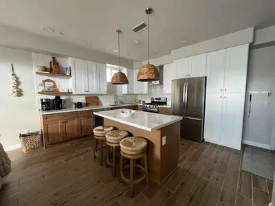 a kitchen with white cabinets and a island with bar stools at Beach Oasis in Carlsbad Village in Carlsbad