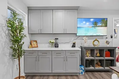 a kitchen with white cabinets and a tv on the wall at Entire Private Home with 3 Bedrooms 3 Bathrooms, House with Yard, King Bed, Prime Location, Available Now in San Diego