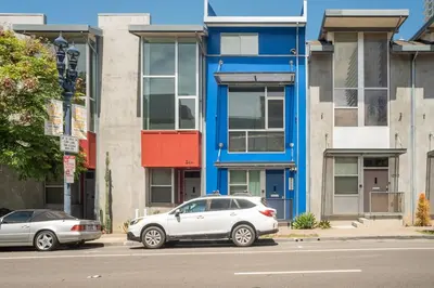 two cars parked in front of a blue building at Modern Surf Themed Home - Heart of Gaslamp in San Diego