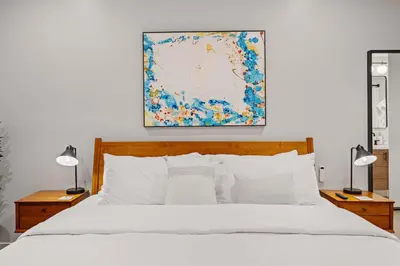 a bedroom with a white bed and a painting on the wall at Del Mar Retreat - Laundry BBQ Firepit AC Patio in San Diego