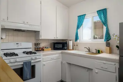 a kitchen with white cabinets and a stove and a window at Chic Beach Retreat - Newly Furnished 1BR in Ocean Beach! in San Diego