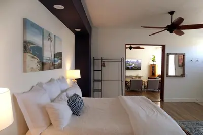 a bedroom with a white bed with a ceiling fan at Saint Ann's Court in Laguna Beach