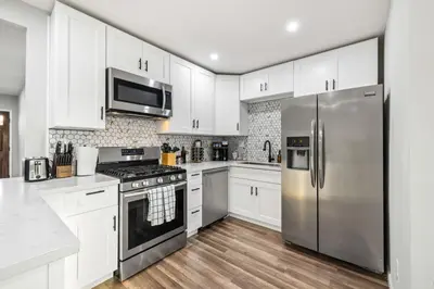 a kitchen with white cabinets and a stainless steel refrigerator at Bay Park Bliss Ocean Views Pickleball and Jacuzzi in San Diego