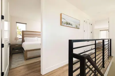 a white bedroom with a bed and a black chair at Coastal Ocean Beach Compound Escape in San Diego