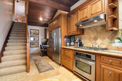a kitchen with wooden cabinets and a staircase at Luxury Oceanfront Home- Upper in Oceanside