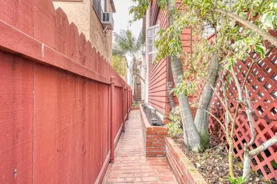 a brick sidewalk next to a red fence at Cute Home Steps from the Sand in San Diego