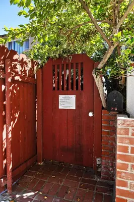a red door with a sign on it next to a brick fence at Cute Home Steps from the Sand in San Diego