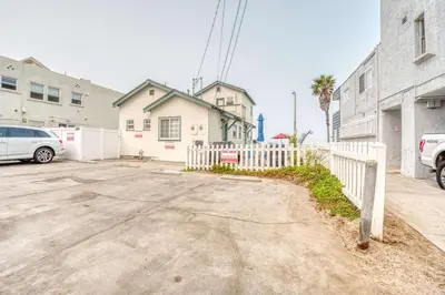 a parking lot with a white fence in front of a house at Cute Home Steps from the Sand in San Diego