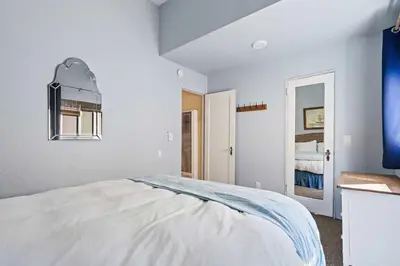 a white bedroom with a bed and a mirror at Cute Home Steps from the Sand in San Diego