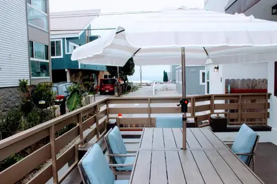 a wooden table with an umbrella on a balcony at Steps from Ocean! Ocean and Bay Views! Rooftop Deck! Two-Car Garage! Renovated! in San Diego