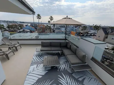 a rooftop patio with a couch and an umbrella at Steps from Ocean! Ocean and Bay Views! Rooftop Deck! Two-Car Garage! Renovated! in San Diego