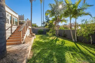 a house with a yard with palm trees and a fence at Designer Home with Yard -Walk to Beach, Shops and More in Solana Beach
