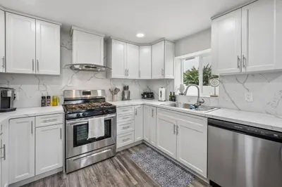 a kitchen with white cabinets and stainless steel appliances at Designer Home with Yard -Walk to Beach, Shops and More in Solana Beach