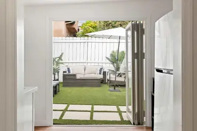 an open door to a patio with a couch and an umbrella at La Jolla Beach Villa - Walk to Windansea Beach in San Diego