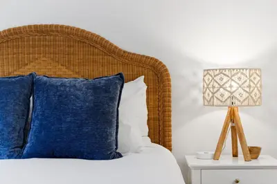 a bed with blue pillows and a lamp on a night stand at Cozy La Jolla Bungalow Near Beach & Village in San Diego