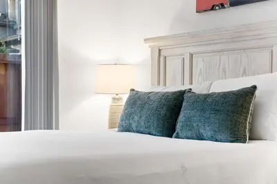 a white bed with blue pillows and a lamp at Cozy La Jolla Bungalow Near Beach & Village in San Diego