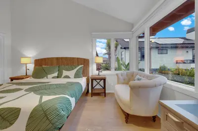 a bedroom with a bed and a chair and a window at Fairway Retreat, Stylish Coastal Home Near Golf, Beaches & Carlsbad Fun in Encinitas