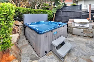 a hot tub sitting on a patio with two white seats at Fairway Retreat, Stylish Coastal Home Near Golf, Beaches & Carlsbad Fun in Encinitas