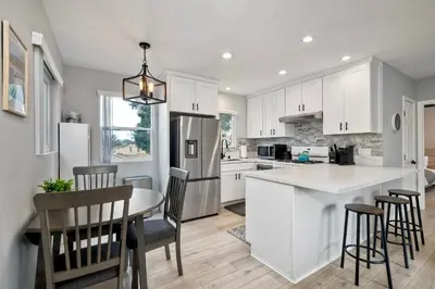 a kitchen with white cabinets and a table and chairs at Luxury Beach Duplex, Sleeps 9, Dog-Friendly, AC, Fire Pit & Grill in Carlsbad