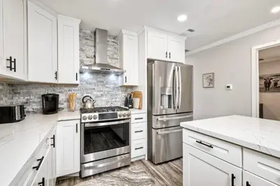 a kitchen with white cabinets and stainless steel appliances at Luxury Beach Duplex, Sleeps 9, Dog-Friendly, AC, Fire Pit & Grill in Carlsbad