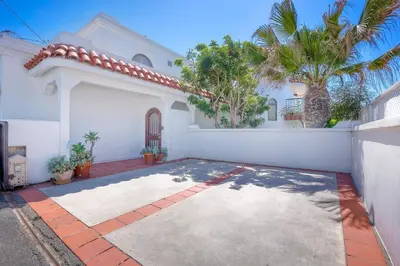 a white house with a palm tree in front of it at Exclusive Beachfront Duplex in Carlsbad Village Ocean Views, Sleeps 9 in Carlsbad