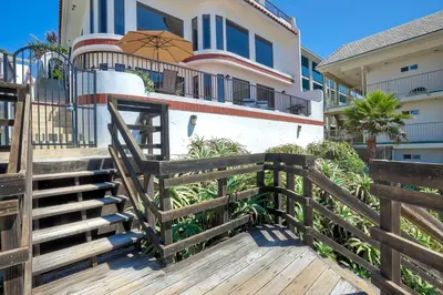 a house with a wooden staircase and an umbrella on it at Exclusive Beachfront Duplex in Carlsbad Village Ocean Views, Sleeps 9 in Carlsbad