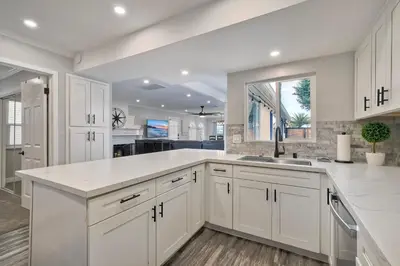 a white kitchen with white cabinets and a sink at Steps to Beach, 2BR Dog Friendly Home with Fire Pit in Carlsbad