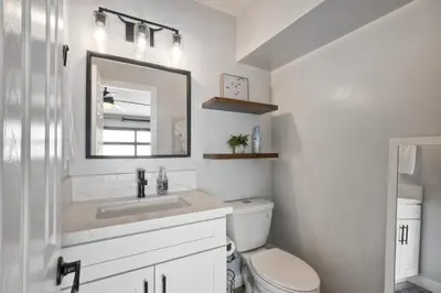 a bathroom with a toilet and a sink and a mirror at Steps to Beach, 2BR Dog Friendly Home with Fire Pit in Carlsbad