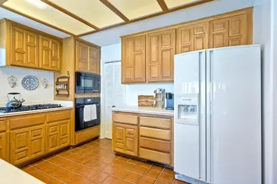 a kitchen with wooden cabinets and a white refrigerator at Direct Beach Access, Views, Carlsbad 2BR Upper Unit in Carlsbad