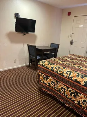 a hotel room with a bed and a table and a tv at San Diego Inn in San Diego