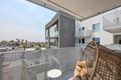 a balcony with a rattan chair on a building at NEW LUX Modern Retreat Views Parking Workspaces in San Diego