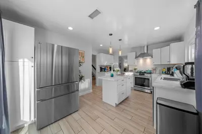a large kitchen with white cabinets and stainless steel appliances at Entire Private Home with 3 Bedrooms, Hot Tub, King Bed, Garage, Grand View, Available Now in San Diego