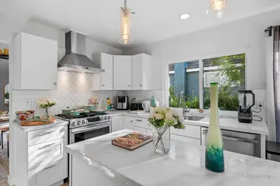 a kitchen with white cabinets and a vase of flowers on a counter at Entire Private Home with 3 Bedrooms, Hot Tub, King Bed, Garage, Grand View, Available Now in San Diego