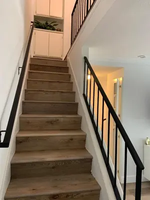a staircase with wooden floors and black railings at Beautifully Remodeled 2BR Prime Irvine Location in Irvine