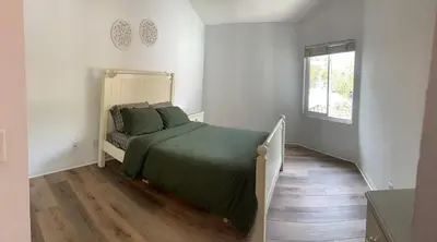 a bedroom with a bed with a green comforter and a window at Beautifully Remodeled 2BR Prime Irvine Location in Irvine