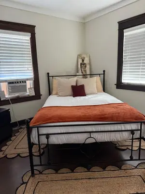 a bed in a bedroom with two windows at Cozy cottage in San Diego