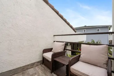 a balcony with wicker chairs and a white wall at New Cozy Leucadia Beach House with parking in Encinitas