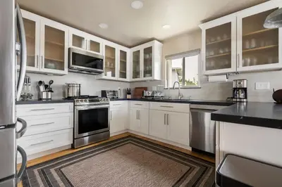 a kitchen with white cabinets and stainless steel appliances at New Cozy Leucadia Beach House with parking in Encinitas