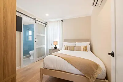 a white bedroom with a bed and a bathroom at Renovated Coastal 2BR - Stylish & Bright in San Diego