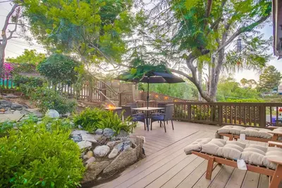 a deck with a table and chairs and an umbrella at 3BRB with Bonus Bedroom, Hot Tub, Tropical Oasis in San Diego