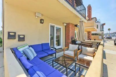 a patio with a blue couch and two chairs at Sail & Sea in Newport Beach